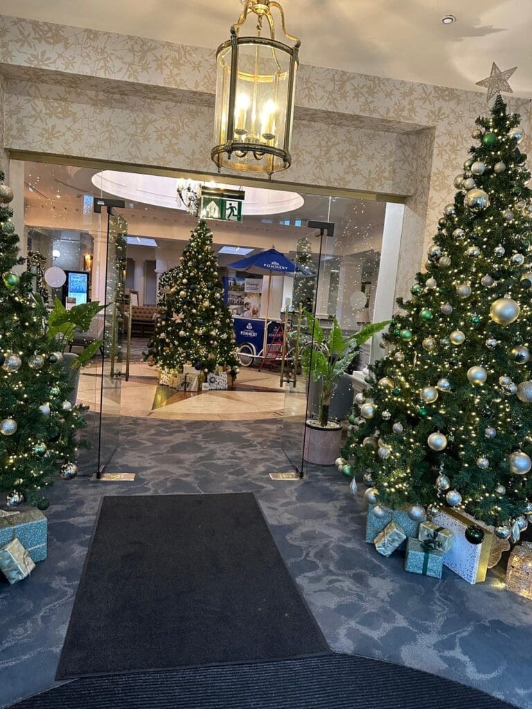 Christmas trees with warm lights and wrapped presents in a hotel entrance lobby