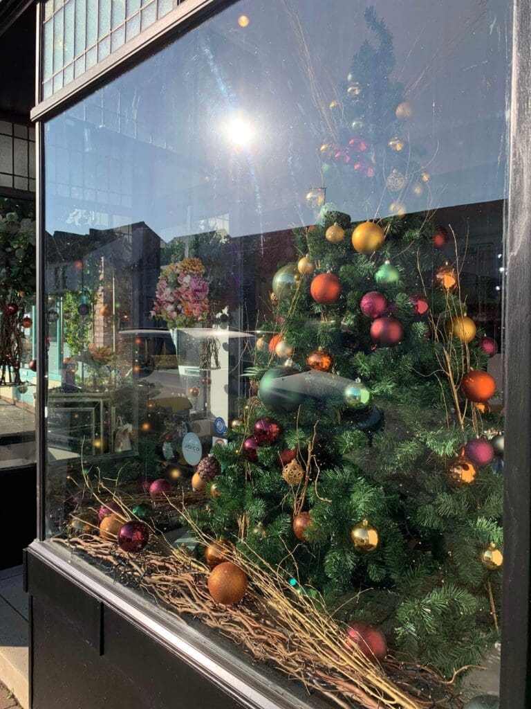 Shop window display with a Christmas tree dressed in red, gold and green baubles