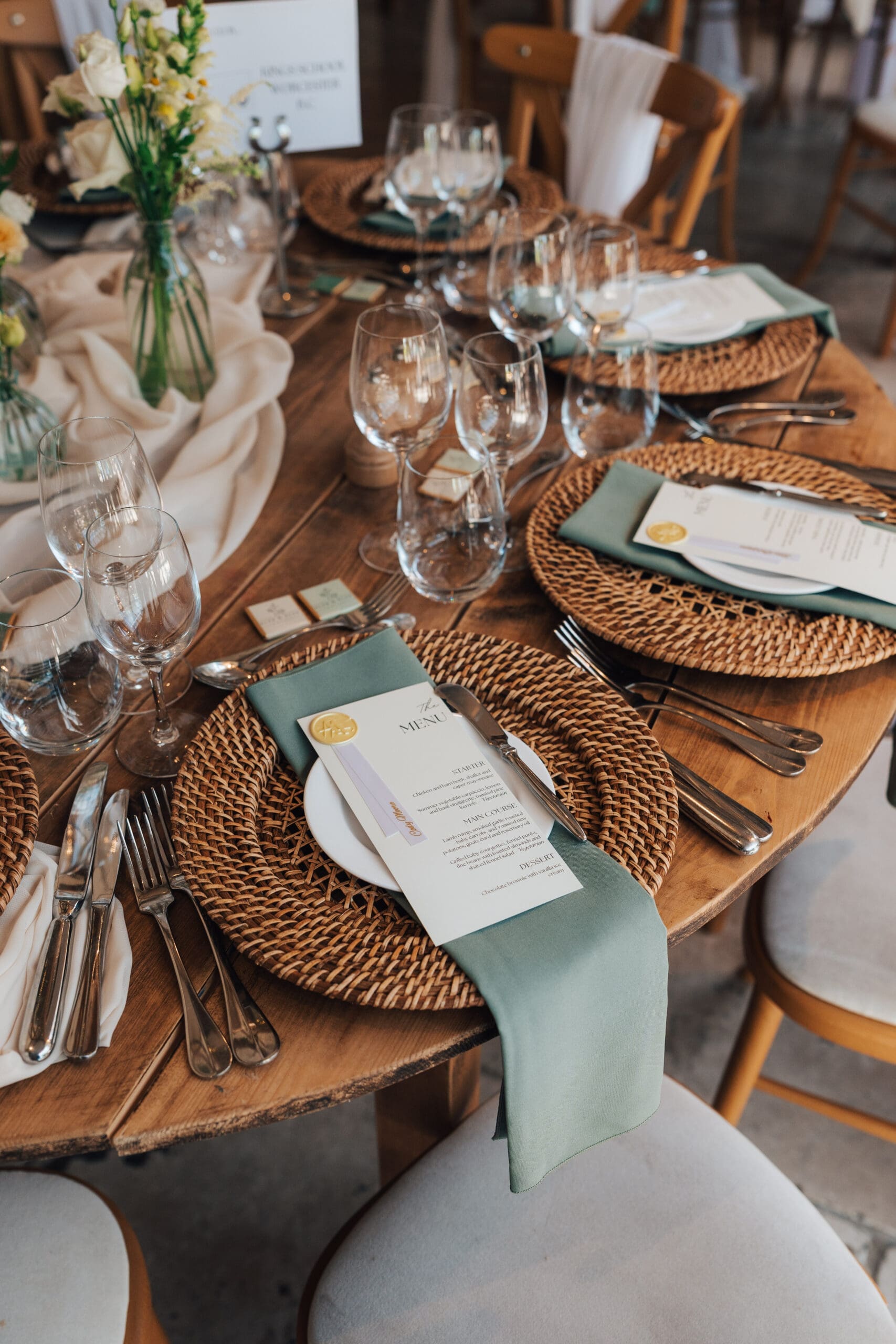 Rustic wedding table setting with rattan charger plates and sage green napkins