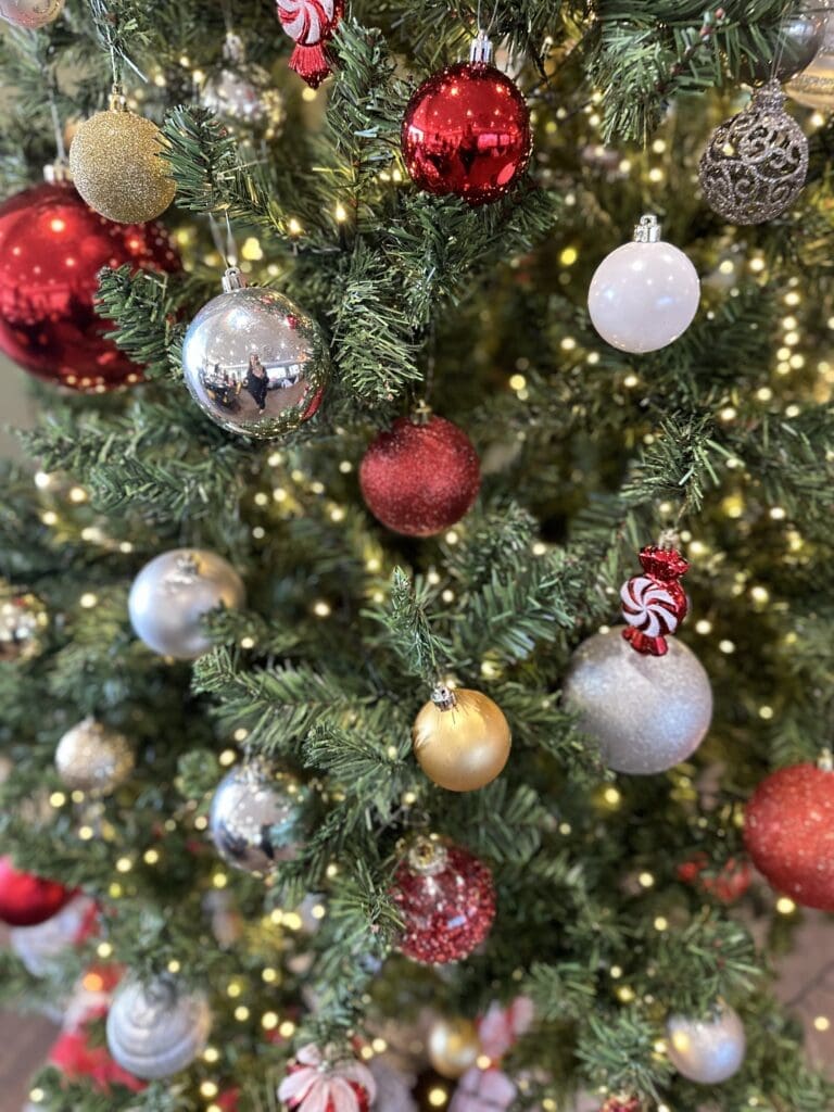 Close-up of a Christmas tree with red, silver and gold baubles and warm white lights