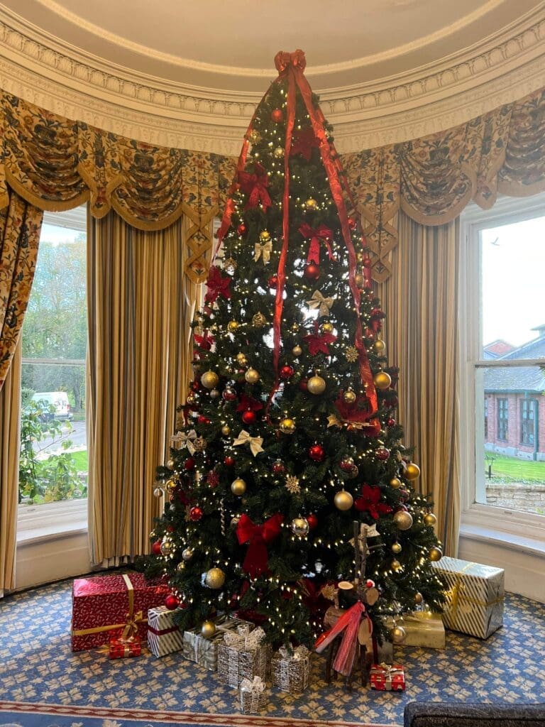 Decorated Christmas tree with presents in a Worcestershire country house drawing room