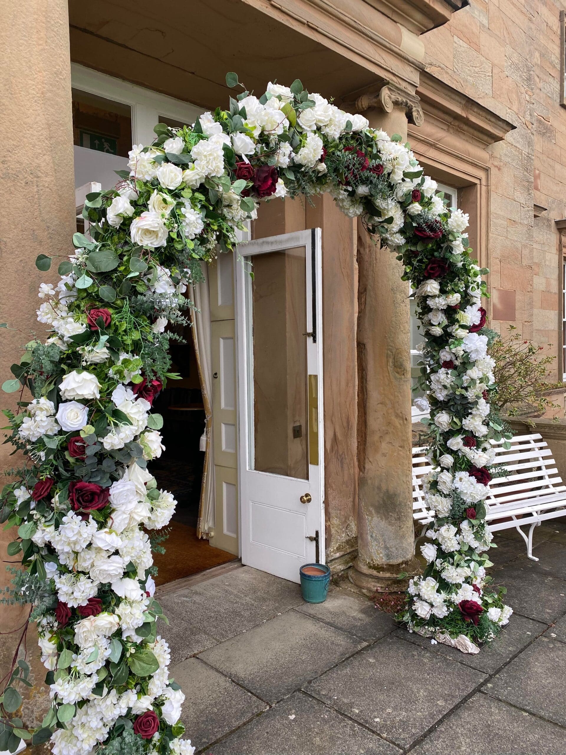 White and burgundy floral arch in a stone doorway at Hagley Hall