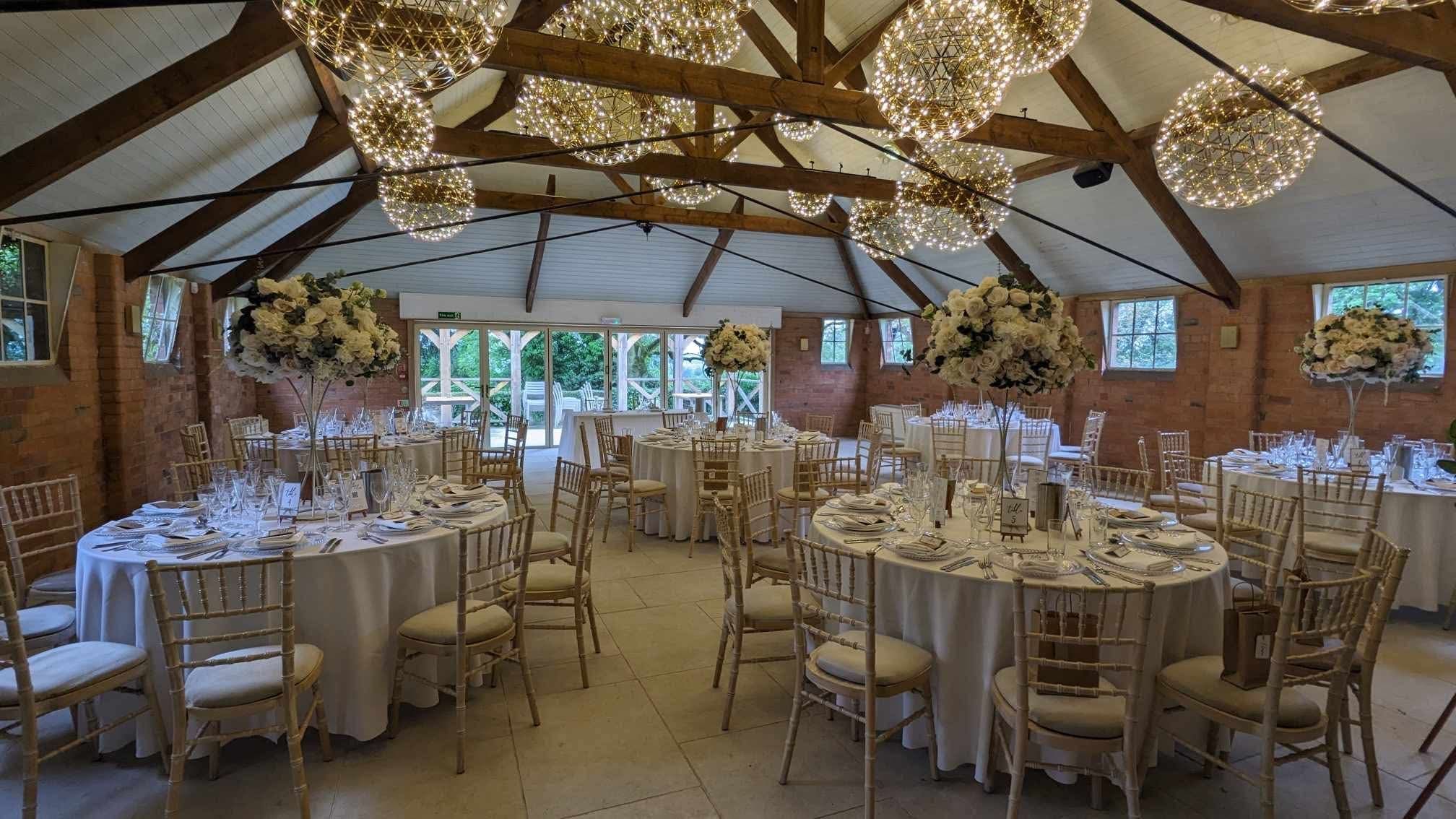 Hanging wicker light shades above round wedding tables at Gorcott Hall