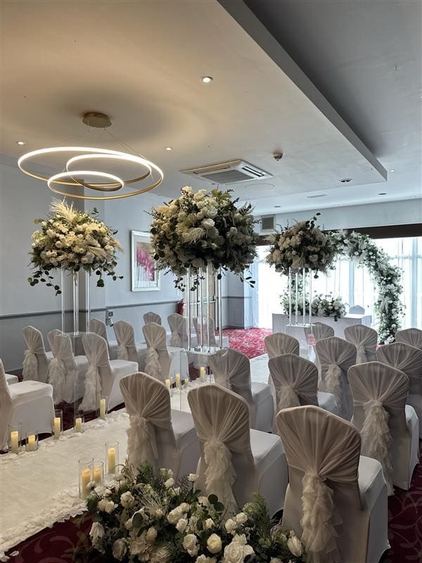 Tall white floral centrepieces and white chair covers at Stourport Manor