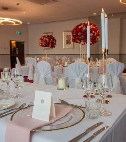Wedding place setting with red florals and pink napkins at Stourport Manor