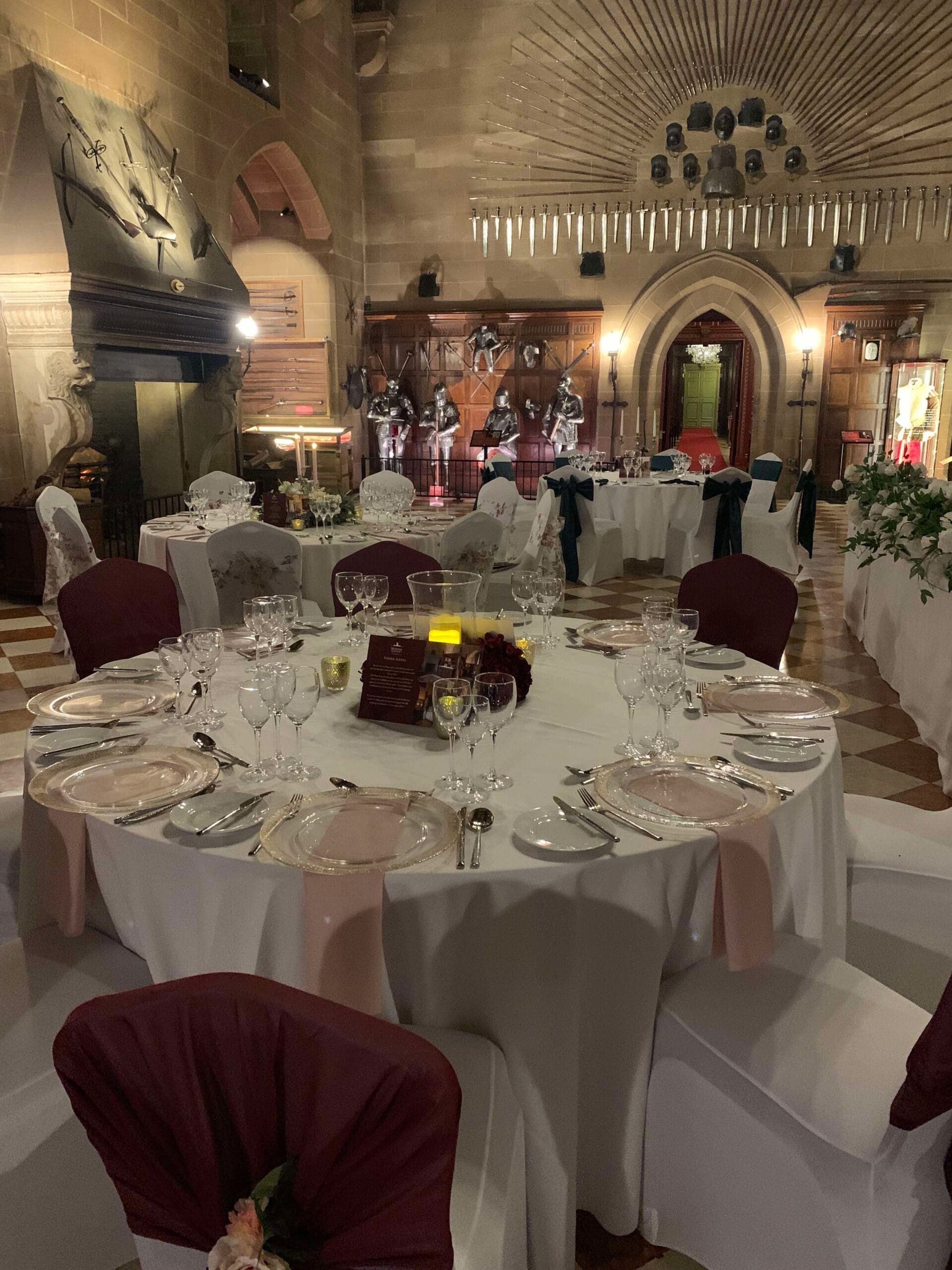 Stone great hall set with round wedding tables at Warwick Castle