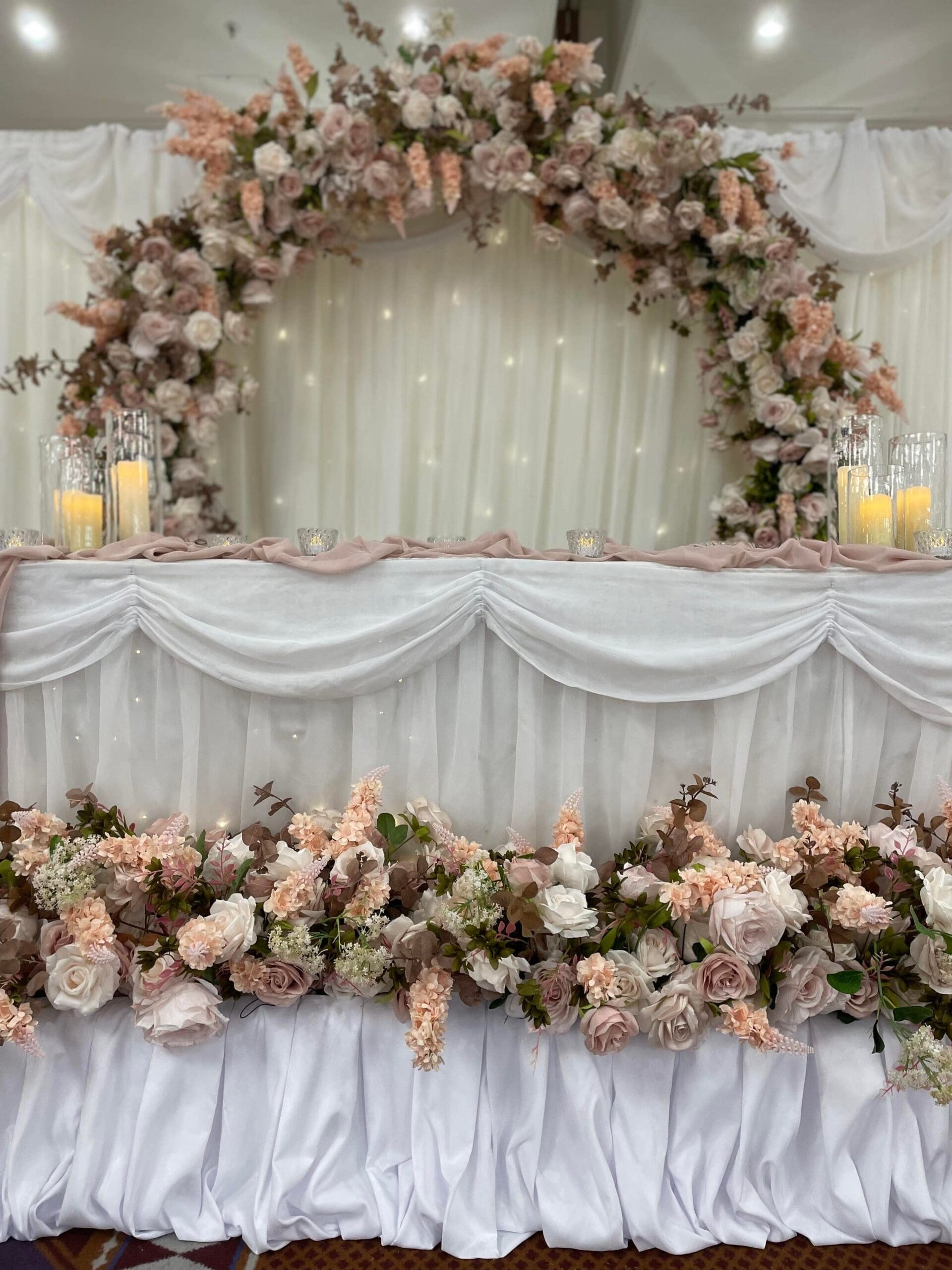 Blush floral arch above a draped top table at the National Conference Centre Birmingham