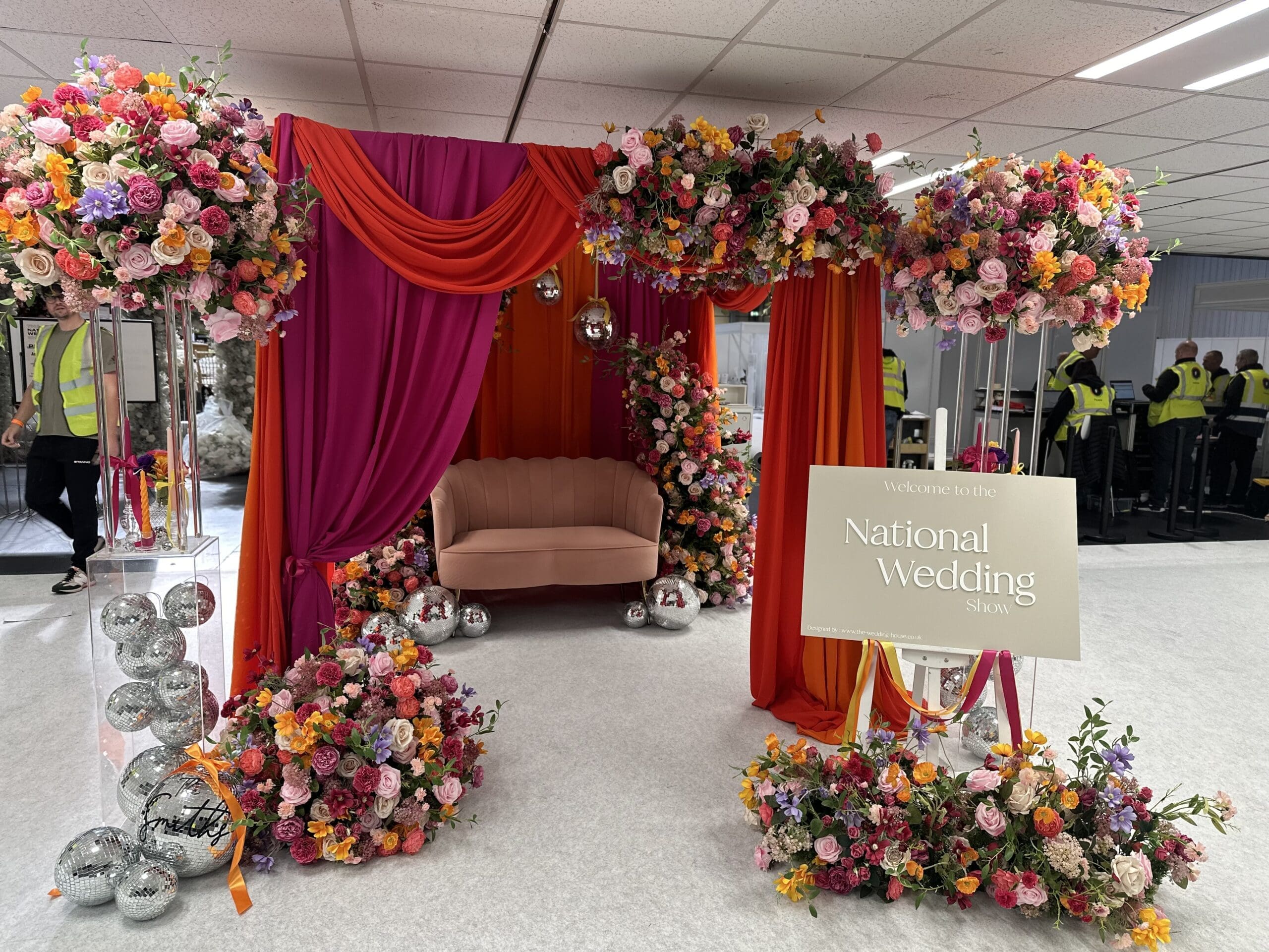 Red and pink draped backdrop with disco balls and bright florals