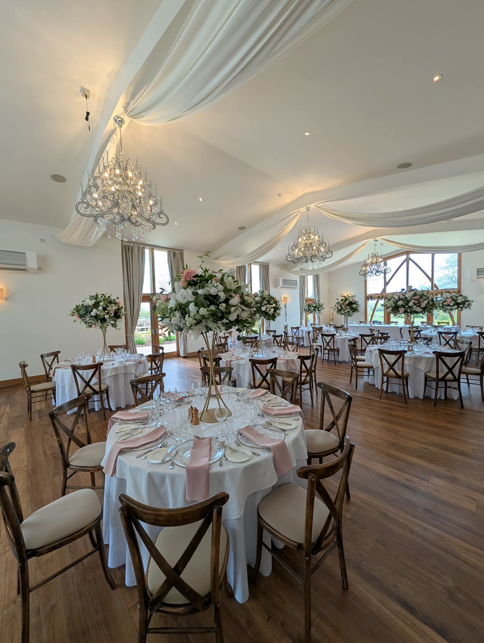 Round wedding tables with tall floral centrepieces and pink table decor at Mythe Barn