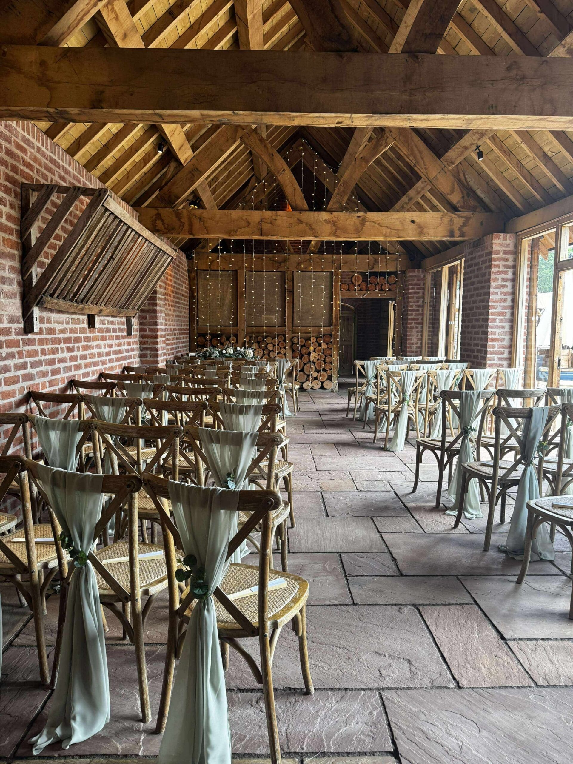 rustic barn wedding ceremony setup at Bridal Barn with wooden chairs and sage green chair decor